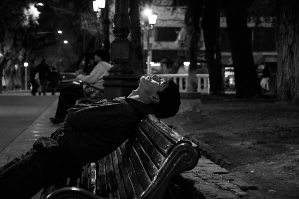 Chico tumbado en un banco soñando.